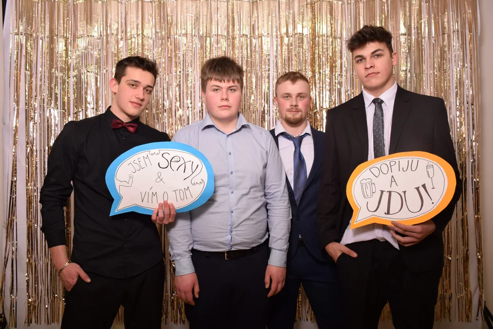 Kluci v oblecích s vtipnými cedulkami ve fotokoutku